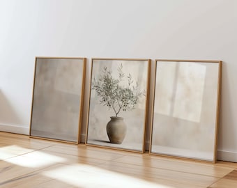 Puede incluir: Tres impresiones enmarcadas con un fondo beige apagado. La impresión central presenta una pintura de acuarela de una rama de olivo verde en una maceta de terracota.