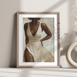 May include: A framed print of a watercolour painting depicting a woman in a white dress with a gold necklace. The woman is standing with her hand on her hip and looking to the side. The background is a soft, muted beige.