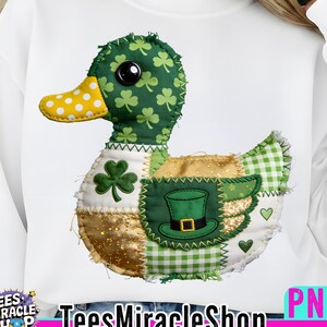 Puede incluir: Sudadera blanca con un diseño de pato patchwork con elementos del Día de San Patricio. El pato tiene una cabeza verde con tréboles, un pico amarillo con lunares y un cuerpo con un sombrero verde, tréboles y detalles dorados. El texto "TeesMiracleShop" está en la parte inferior.