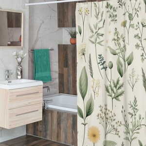 Puede incluir: Una cortina de ducha blanca con un patr&oacute;n floral verde y amarillo. La cortina est&aacute; colgada en un ba&ntilde;o con una ba&ntilde;era blanca y un suelo de madera.
