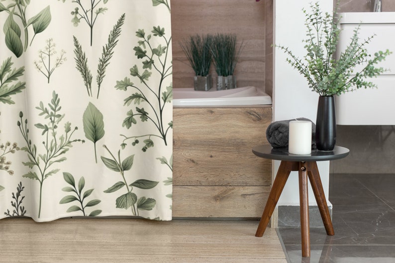 Puede incluir: Una cortina de ducha blanca con un patr&oacute;n de hojas verdes. La cortina est&aacute; colgada en un ba&ntilde;o con una ba&ntilde;era de madera y una peque&ntilde;a mesa auxiliar con una vela y un jarr&oacute;n de vegetaci&oacute;n.