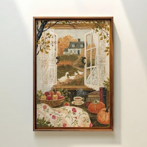 Puede incluir: Un cuadro enmarcado que muestra una ventana abierta con cortinas de encaje blanco que dan a un paisaje rural con una casa y gansos blancos. En primer plano, una cesta de manzanas, una taza, libros y dos calabazas naranjas sobre una mesa.