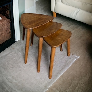 Puede incluir: Tres mesas nido de madera con forma triangular. Las mesas son de madera marrón claro y tienen un acabado liso.