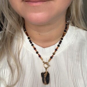 Statement ketting met schild – robijn, carneool, tijgeroog en zwarte toermalijn | Ruwe kristallen hanger | Aarding, brand, beschermingsenergie