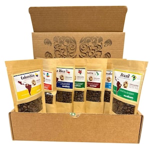 May include: A cardboard box filled with several sealed bags of coffee beans. Each bag is labeled with a country of origin, including Colombia, Brazil, and Costa Rica. The box has a decorative cutout design on the lid.