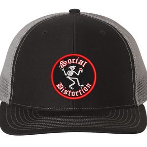 May include: Black and gray trucker hat with a red and white embroidered patch that says "Social Distortion" with a skeleton figure holding a beer.