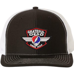 May include: Black and white trucker hat featuring the Grateful Dead logo. The logo includes a red, white, and blue lightning bolt and skull design, with the words "Grateful Dead Since 1965". The hat has a curved brim and a mesh back.