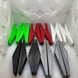 May include: A set of 10 plastic pieces in various colors, including green, red, white, black, and gray. The pieces are shaped like a wedge or a narrow triangle and are arranged in rows.