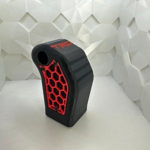 May include: Black and red 3D printed gear shift knob with a honeycomb pattern and the word "TRD" printed on the side.