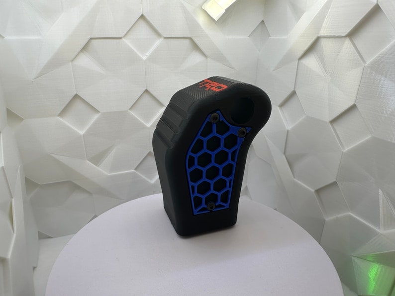 May include: Black 3D printed gear shift knob with a blue honeycomb pattern and the word "TRD" in red lettering.