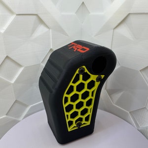 May include: Black gear shift knob with a yellow honeycomb pattern and the word "TRD" in red lettering.