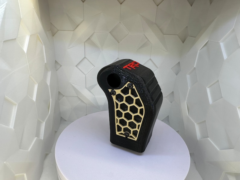 May include: Black 3D printed gear shift knob with a gold honeycomb design and the word "TRD" in red lettering.