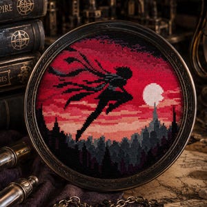 May include: A circular cross-stitch embroidery piece framed in dark metal, depicting a black silhouette of a figure leaping against a vibrant red and pink sunset sky with a white moon over a dark cityscape, presented in a detailed, atmospheric setting.