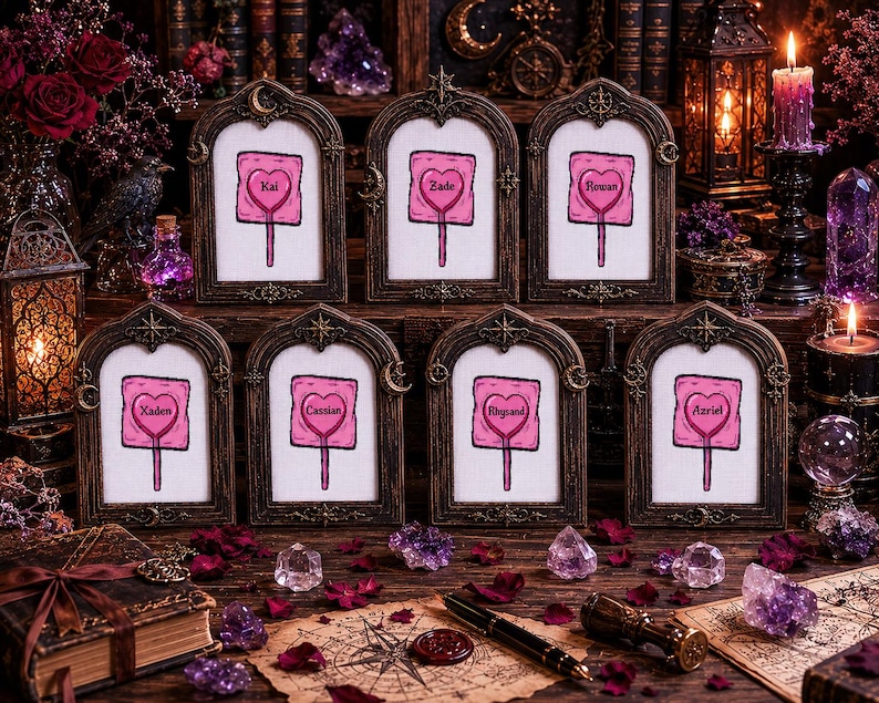 May include: Seven framed artworks with a heart-shaped lollipop design, each bearing a different name in a pink heart. The frames are dark brown with ornate details. The scene is set on a wooden surface with crystals and candles.