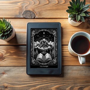 May include: A black and white illustration of a mountain range with a book open in front of it. The illustration is on a black and white e-reader with the text "Velaris City of starlight" on the screen.