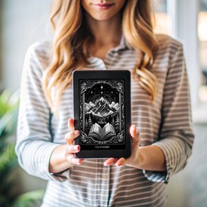 May include: A woman is holding a black e-reader with a cover image of a book with the title "Velaris, City of Nightlight". The cover art is a black and white illustration of a mountain range with a starry sky.