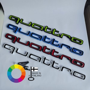 Könnte beinhalten: Fünf "quattro" Embleme in verschiedenen Farben: grün, blau, rot, weiß und schwarz. Die Embleme werden in Finnland hergestellt.