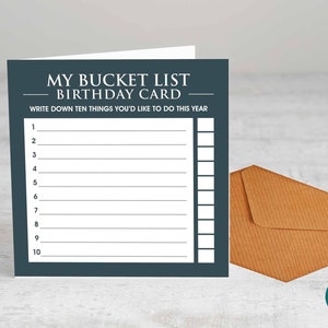Può includere: Un biglietto di auguri di compleanno blu scuro con il testo "My Bucket List Birthday Card" e un elenco di dieci righe vuote per scrivere le cose da fare quest'anno.