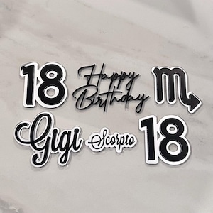 May include: Black and white birthday cake toppers with the numbers "18", the words "Happy Birthday", the name "Gigi", the zodiac sign "Scorpio", and a Scorpio symbol.