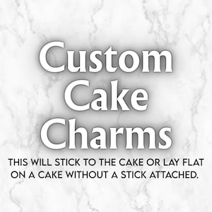 May include: Custom Cake Charms text in a bold serif font against a white marble background. Below the main text, smaller black text reads: THIS WILL STICK TO THE CAKE OR LAY FLAT ON A CAKE WITHOUT A STICK ATTACHED. The design is clean and informative.