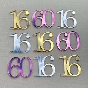 May include: Nine decorative number cutouts in gold, pink, and silver. The numbers are arranged in a grid pattern, with the numbers 16 and 60 repeated. The cutouts have a reflective, metallic finish.