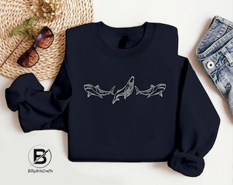 Peut inclure: Un sweat-shirt bleu marine avec un contour blanc de trois requins, dont un requin baleine, sur le devant.