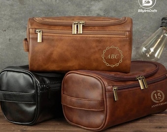 May include: Three brown leather travel bags with zippers. The top bag has the initials "ABC" in a gold circle. The middle bag is black. The bottom bag has a gold circle with the text "15 Years Anniversary".