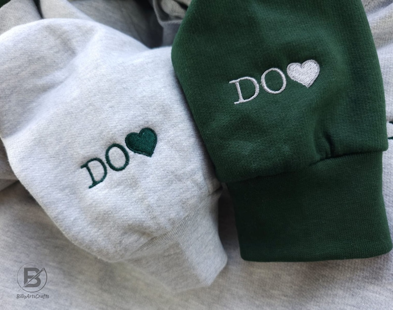 May include: Two hooded sweatshirts with the word "DO" embroidered on them. One sweatshirt is grey with a green heart and the other is green with a white heart.