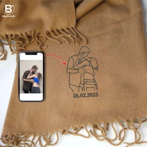 May include: A brown scarf with a personalized embroidered design of a couple embracing. The design includes the date "26.02.2023".