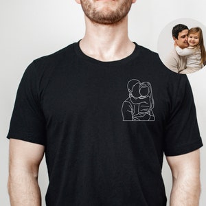 May include: Black t-shirt with a white line drawing of a father and daughter hugging.