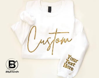 May include: White sweatshirt with gold lettering that says "Custom" on the front and "Your Text Here" on the sleeve.