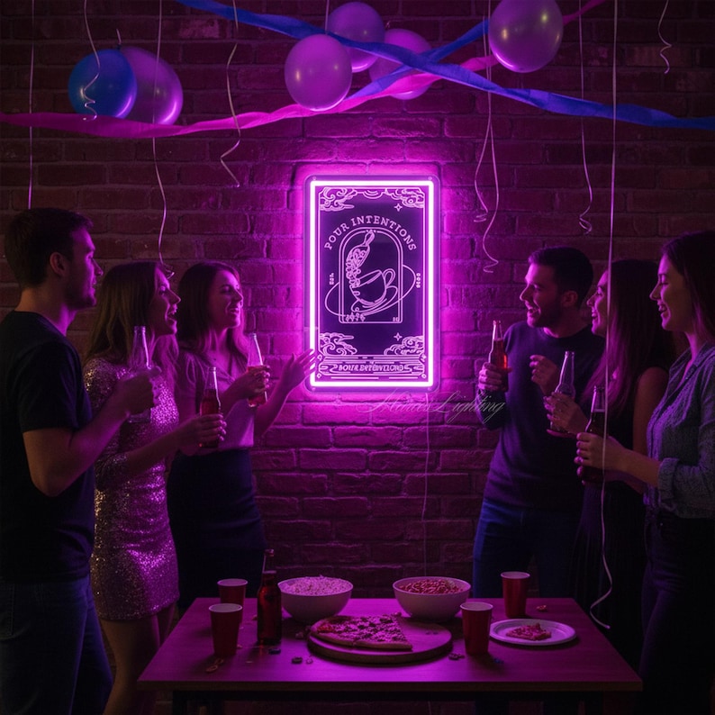 K&ouml;nnte beinhalten: Ein leuchtendes pinkfarbenes Neon-Schild mit der Aufschrift "Your Intentions" in einem dekorativen Rahmen. Das Schild h&auml;ngt an einer Backsteinmauer, mit Partydekorationen und Menschen um einen Tisch mit Essen und Getr&auml;nken.