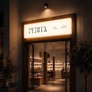 Può includere: Vista esterna di un laboratorio di ceramica, "PERITA", con un'insegna luminosa sopra l'ingresso. L'insegna recita anche "Pottery Workshop" e "Open Daily 09:00-21:00". L'interno del negozio è visibile attraverso le porte a vetri aperte, mostrando ceramiche su scaffali e tavoli.