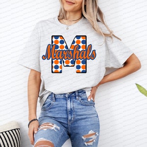 May include: A gray t-shirt with a blue and orange polka dot letter "M" and the text "Marshals" in a blue cursive font.