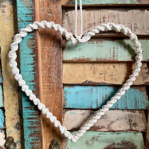 Peut inclure: Une couronne en forme de cœur en corde blanche suspendue à une porte en bois peinte en bleu et vert.