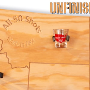 K&ouml;nnte beinhalten: Unfertiges Holzbrett mit einer darauf eingegrabenen Karte der Vereinigten Staaten. Das Brett hat 50 Halter f&uuml;r Schnapsgl&auml;ser und den Text "All 50 Shots Made in USA".