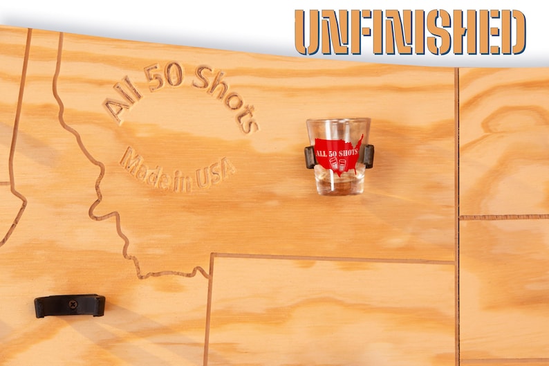 K&ouml;nnte beinhalten: Unfertiges Holzbrett mit einer darauf eingegrabenen Karte der Vereinigten Staaten. Das Brett hat 50 Halter f&uuml;r Schnapsgl&auml;ser und den Text "All 50 Shots Made in USA".