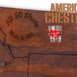 K&ouml;nnte beinhalten: Ein Holz-Shotglas-Halter mit einer geschnitzten Umrandung der Vereinigten Staaten. Der Halter ist aus amerikanischem Kastanienholz gefertigt und tr&auml;gt die Aufschrift "All 50 Shots Made in USA". Ein Shotglas mit einem rot-wei&szlig;em amerikanischen Flaggenmuster ist im Lieferumfang enthalten.