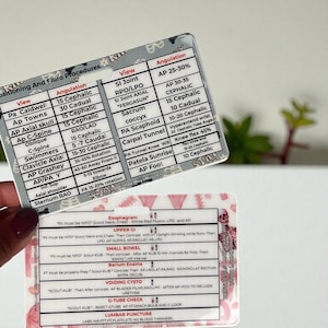 May include: Two medical procedure reference cards with detailed information on positioning and fluoroscopy. The cards feature text in black font, including views, angulation, and specific instructions for various procedures. The cards are held by a person.