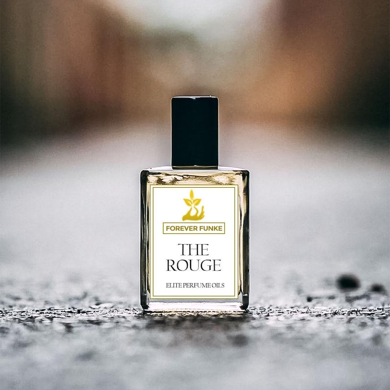 Puede incluir: Botella de perfume rectangular transparente con tap&oacute;n negro. La etiqueta muestra "FOREVER FUNKE" sobre "THE ROUGE" y "ELITE PERFUME OILS". Contiene un l&iacute;quido &aacute;mbar claro.