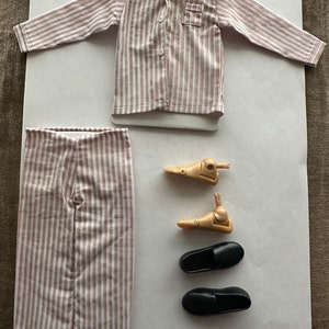 May include: A striped pajama set with a long-sleeved shirt and pants. The shirt has a button-up front and a pocket on the left chest. The pants have a straight leg. The set is pink and white.