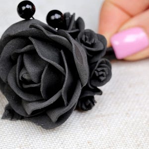 a woman's hand is holding a black rose