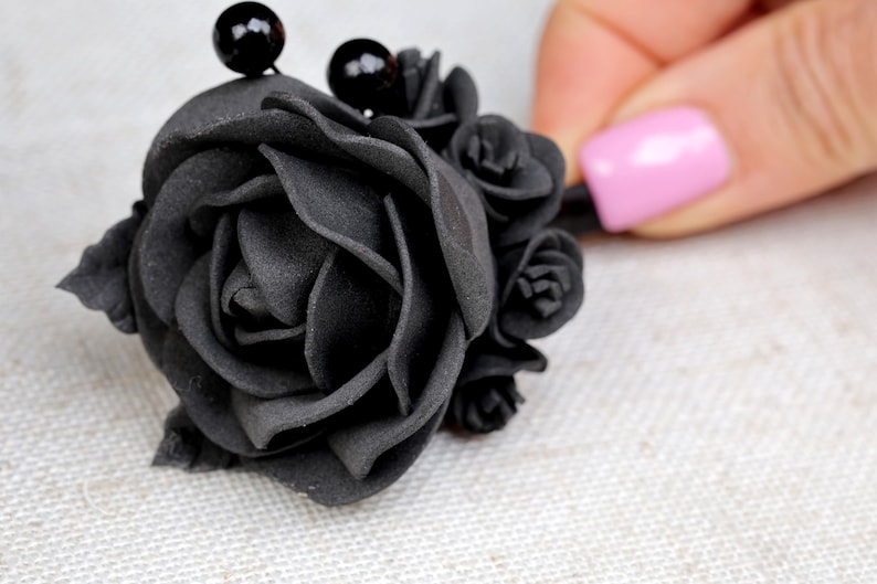 a woman's hand is holding a black rose