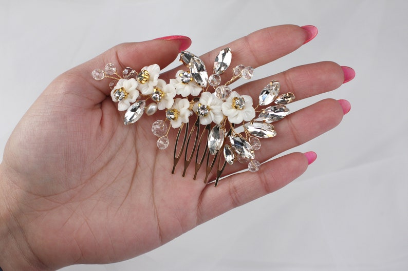 a woman's hand holding a hair comb with flowers on it