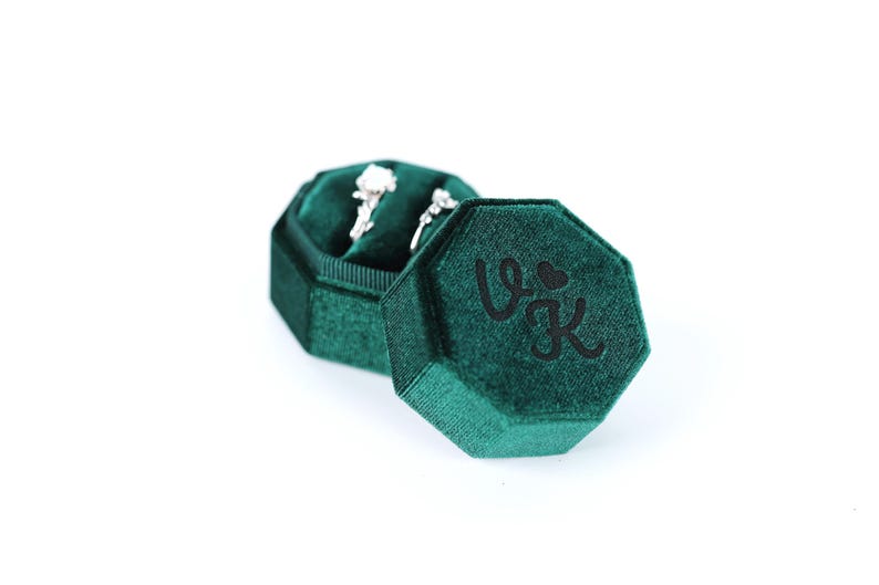 A green velvet jewelry box containing two diamond earrings.