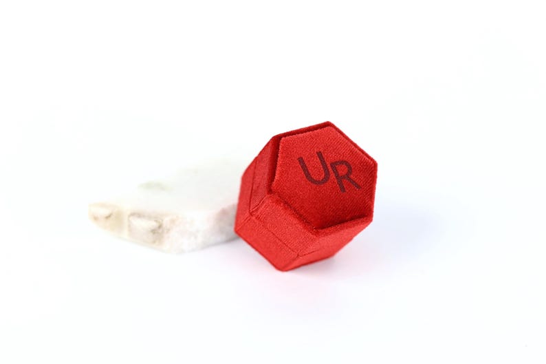 A red hexagonal object with the letters "UR" printed on it, placed on a white surface.