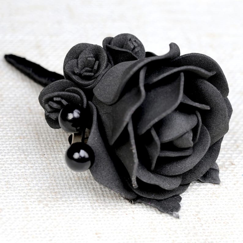 a close up of a black rose on a white surface