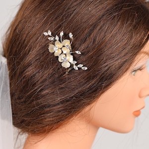 A close-up of a woman's head with a decorative hair accessory featuring small flowers or leaves.