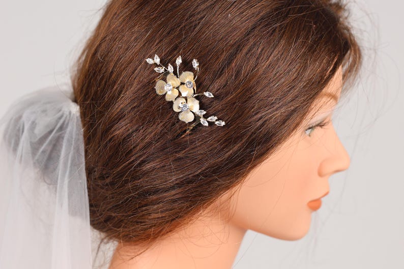 A close-up of a woman's head with a decorative hair accessory featuring small flowers or leaves.