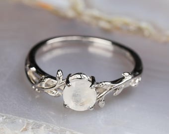 Op de afbeelding: Een zilveren ring met een delicaat takontwerp en een ronde maansteen.